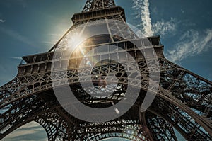 Bottom view of Eiffel Tower made in iron and Art Nouveau style, with sunny blue sky in Paris.